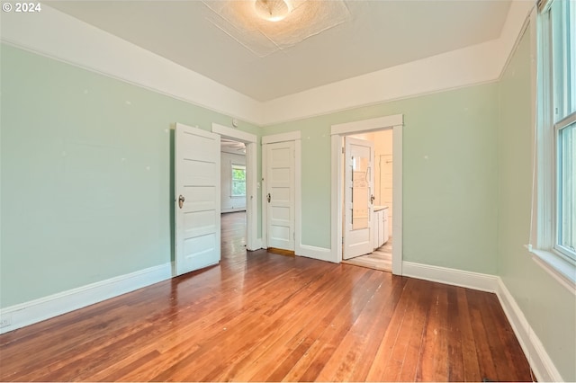 unfurnished bedroom featuring connected bathroom and hardwood / wood-style floors