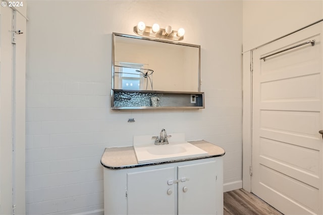 bathroom with hardwood / wood-style flooring, vanity, and tile walls