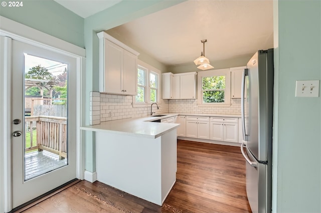 kitchen featuring dark hardwood / wood-style floors, stainless steel refrigerator, white cabinetry, sink, and hanging light fixtures