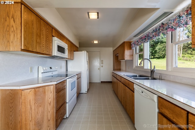 kitchen with white appliances, light tile patterned flooring, and sink