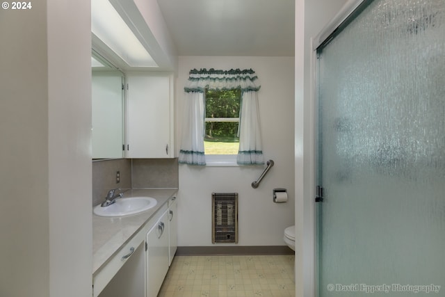 bathroom with toilet, decorative backsplash, heating unit, a shower with door, and vanity