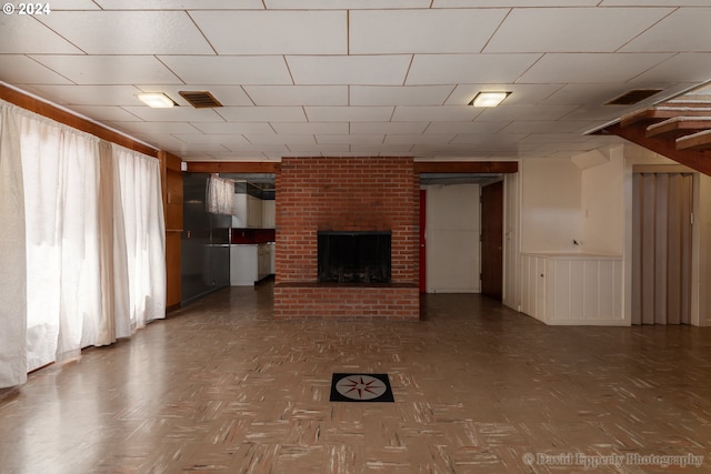 unfurnished living room with a fireplace, parquet floors, and a wealth of natural light