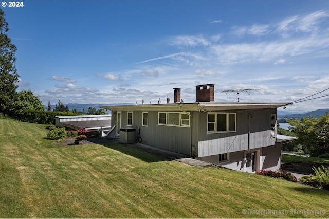 rear view of property featuring central air condition unit and a yard