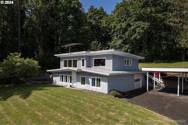 view of front of home featuring a carport, a front lawn, and a garage