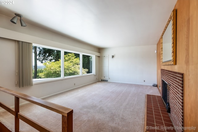 unfurnished living room with a brick fireplace and carpet