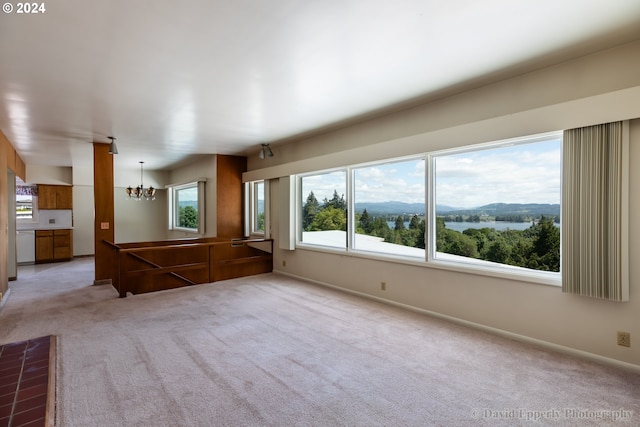 empty room featuring light colored carpet, a chandelier, and a mountain view