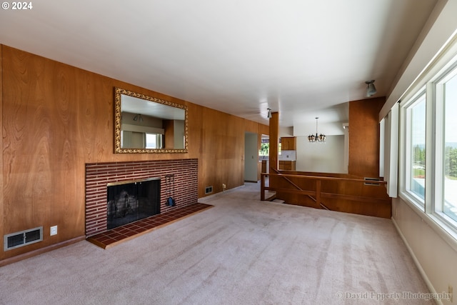 unfurnished living room featuring a tiled fireplace, wood walls, and a healthy amount of sunlight