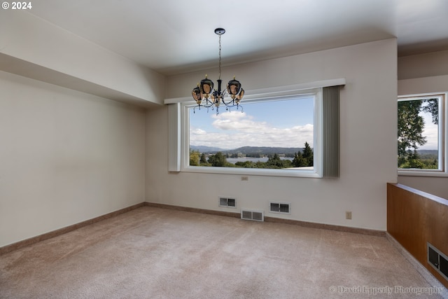 unfurnished dining area featuring light carpet, a chandelier, and a wealth of natural light