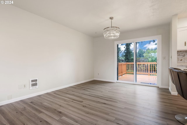 unfurnished dining area featuring hardwood / wood-style flooring, heating unit, and a chandelier