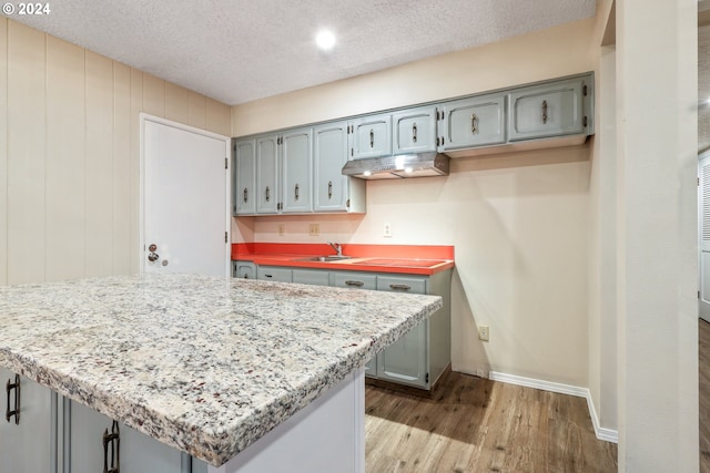 kitchen with gray cabinets, sink, light hardwood / wood-style flooring, and a textured ceiling