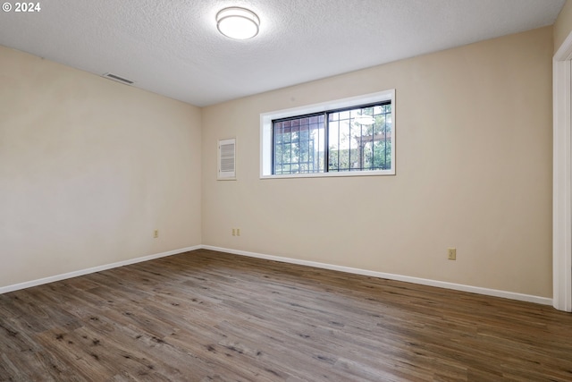 empty room with a textured ceiling and dark hardwood / wood-style flooring