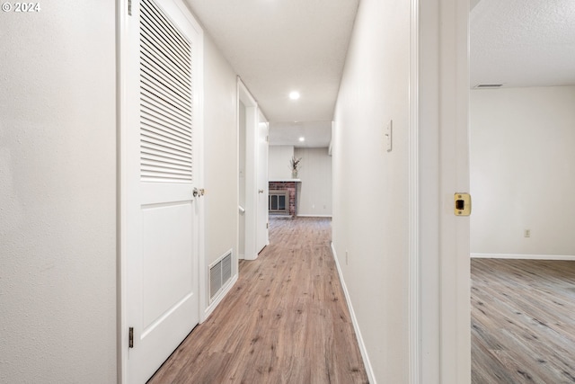 corridor with a textured ceiling and light wood-type flooring