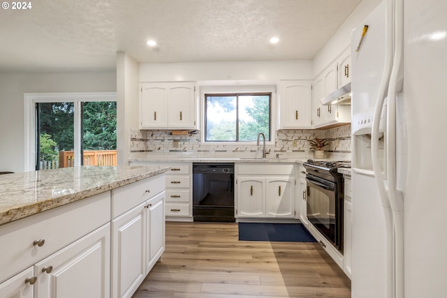 kitchen with white cabinetry, black appliances, sink, and a wealth of natural light