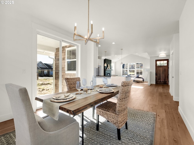 dining space with wood-type flooring, a chandelier, and vaulted ceiling