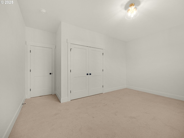 unfurnished bedroom featuring light colored carpet and a closet