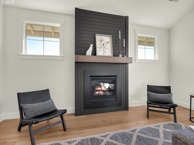 sitting room with a large fireplace and wood-type flooring