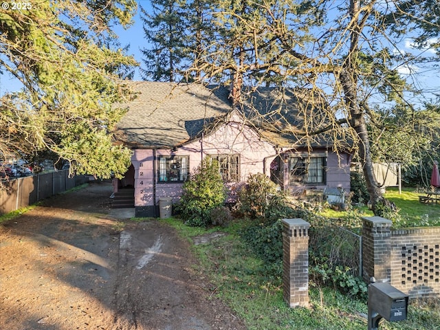 bungalow featuring a shingled roof and fence