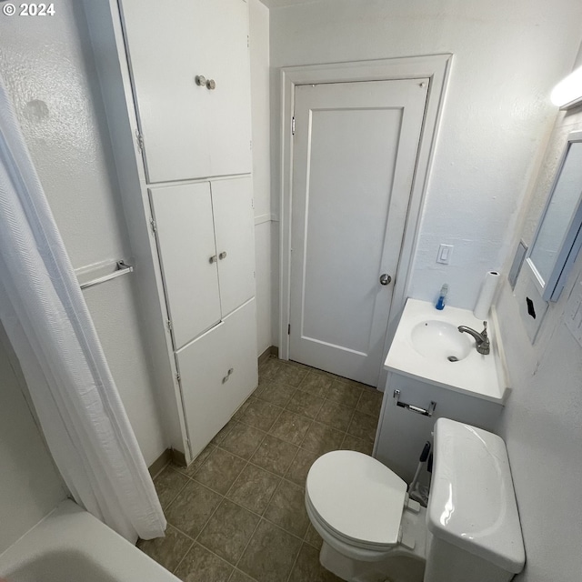 bathroom featuring tile patterned flooring, vanity, a bathing tub, and toilet