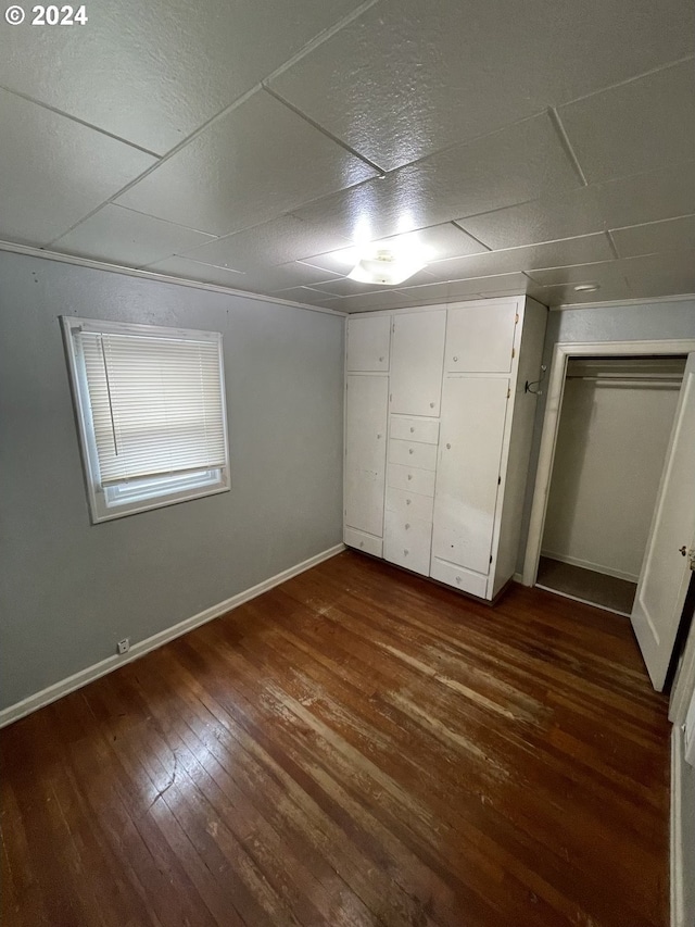 unfurnished bedroom with dark hardwood / wood-style flooring and a drop ceiling