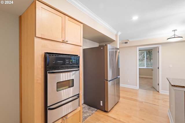 kitchen with light brown cabinets, crown molding, appliances with stainless steel finishes, and light hardwood / wood-style flooring