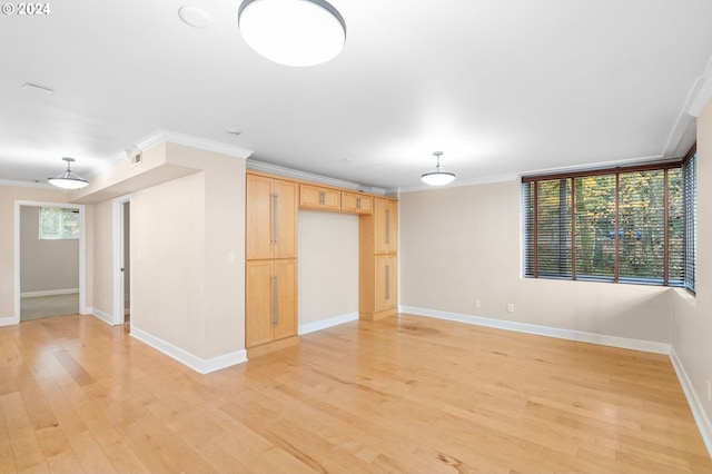 empty room with a wealth of natural light, crown molding, and light hardwood / wood-style flooring