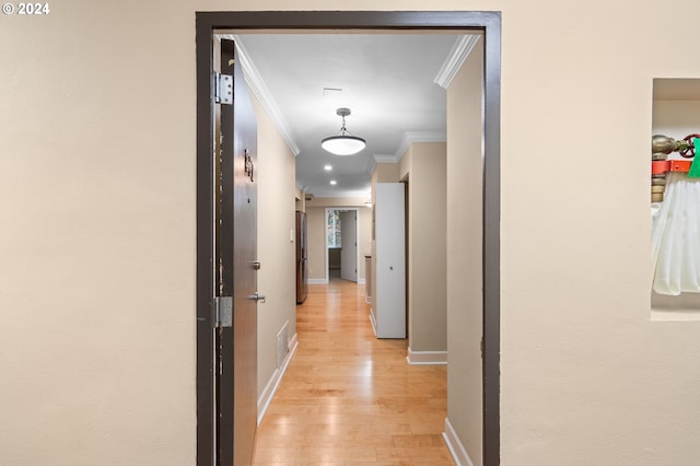 hall with light wood-type flooring and ornamental molding