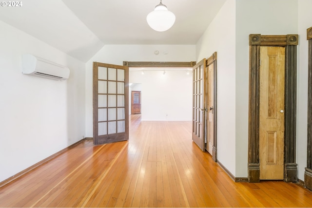 hall featuring vaulted ceiling, french doors, a wall mounted air conditioner, and hardwood / wood-style flooring