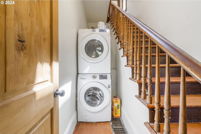 washroom with wood-type flooring and stacked washing maching and dryer