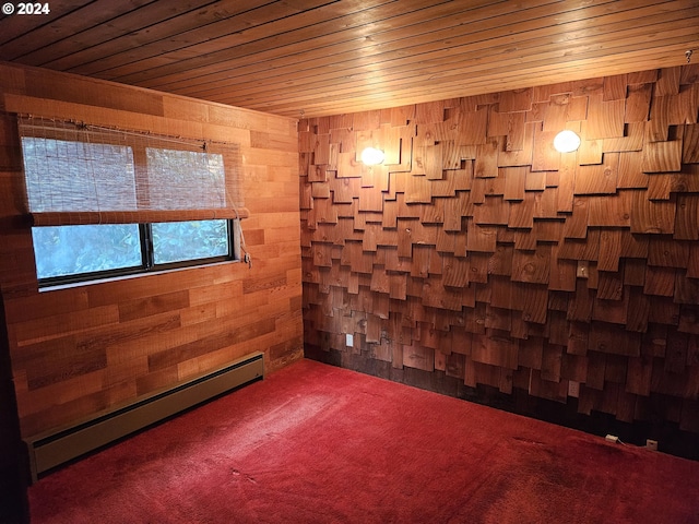 empty room with wood walls, carpet floors, wooden ceiling, and a baseboard heating unit