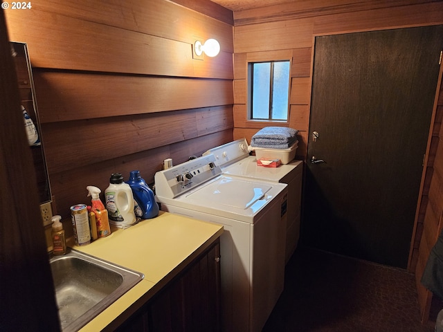 laundry area featuring cabinets, sink, wooden walls, and washing machine and clothes dryer