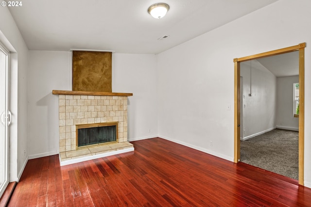 unfurnished living room featuring a tile fireplace, wood-type flooring, and a wealth of natural light