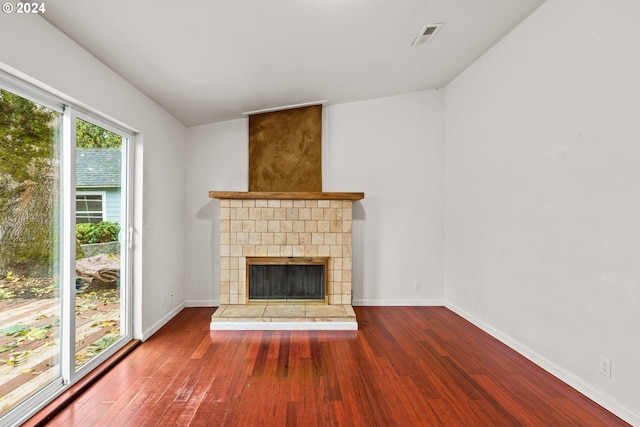 unfurnished living room with a tile fireplace, hardwood / wood-style flooring, and lofted ceiling