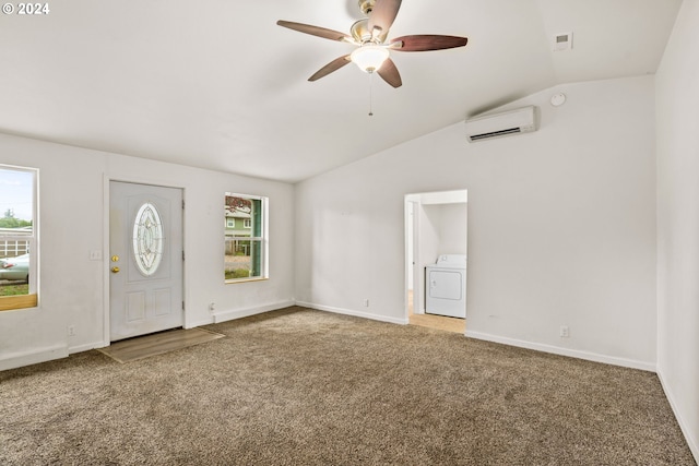 carpeted foyer entrance featuring a wall unit AC, washer / clothes dryer, a wealth of natural light, and vaulted ceiling