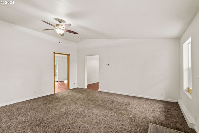 spare room with ceiling fan, dark carpet, and lofted ceiling