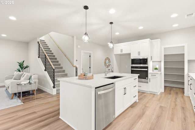 kitchen featuring stainless steel dishwasher, white cabinets, and a kitchen island with sink