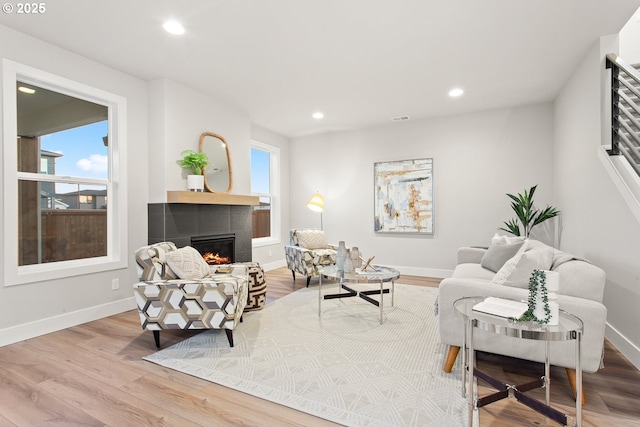 living room featuring light hardwood / wood-style floors and a tiled fireplace