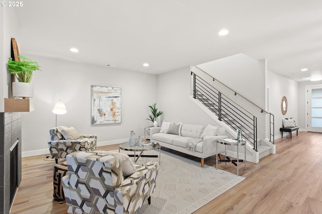 living room featuring a tile fireplace and light hardwood / wood-style floors