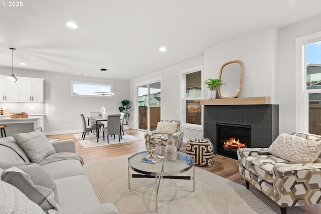 living room featuring a tiled fireplace and light wood-type flooring