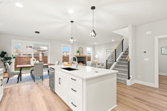 kitchen featuring white cabinetry, sink, pendant lighting, and a kitchen island with sink