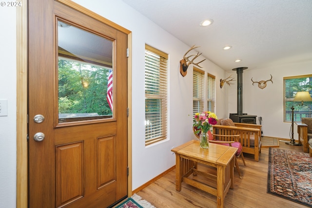 entryway with a wood stove and light wood-type flooring