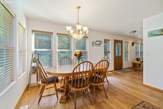 dining space with a chandelier, a textured ceiling, and light hardwood / wood-style flooring