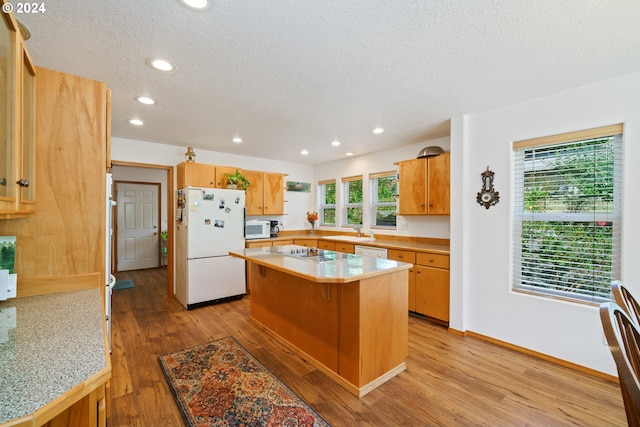 kitchen featuring light wood-type flooring, white appliances, a kitchen island, and plenty of natural light