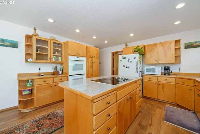 kitchen featuring a textured ceiling, a center island, white appliances, and light hardwood / wood-style flooring