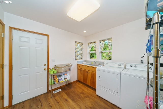 laundry area with washing machine and dryer, sink, cabinets, and hardwood / wood-style flooring