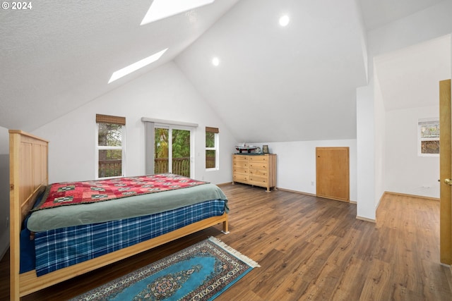 bedroom featuring lofted ceiling with skylight, wood-type flooring, and a textured ceiling