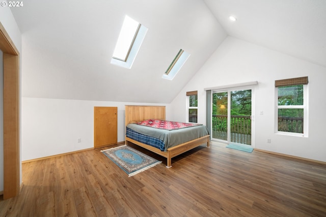 bedroom featuring access to outside, hardwood / wood-style flooring, and vaulted ceiling with skylight