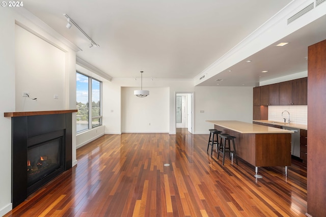 unfurnished living room with sink, dark hardwood / wood-style flooring, and rail lighting