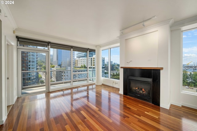 unfurnished living room with crown molding, track lighting, and hardwood / wood-style floors