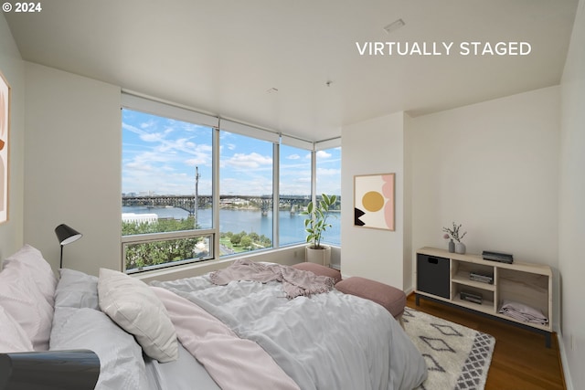 bedroom with a water view and dark wood-type flooring