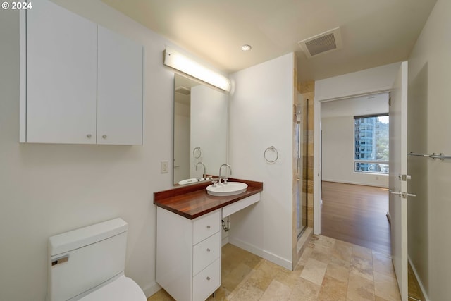 bathroom featuring a shower with door, vanity, and toilet